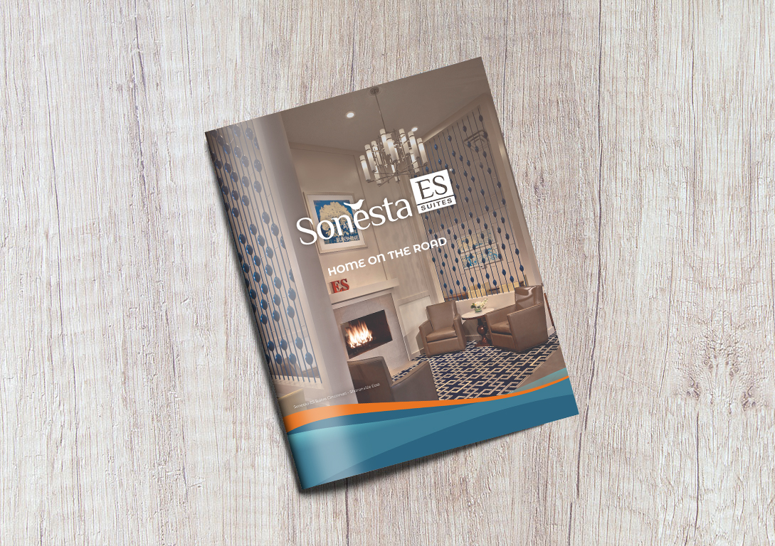 The Sonesta ES Suites Brand Brochure in front of a gray, wooden background.