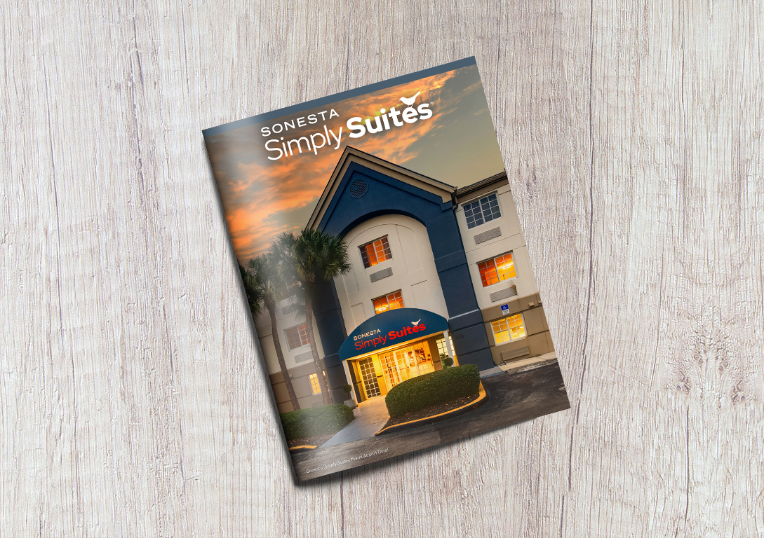 The Sonesta Simply Suites Brand Brochure in front of a gray, wooden background.