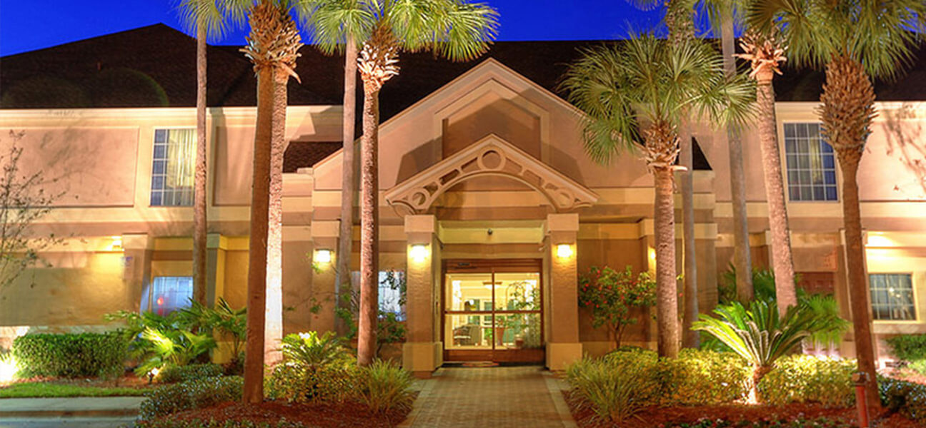 Sonesta ES Suites Orlando Lake Buena Vista hotel's front entrance exterior surrounded with palm trees
